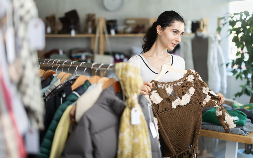 Young woman choosing cardigan in clothing store