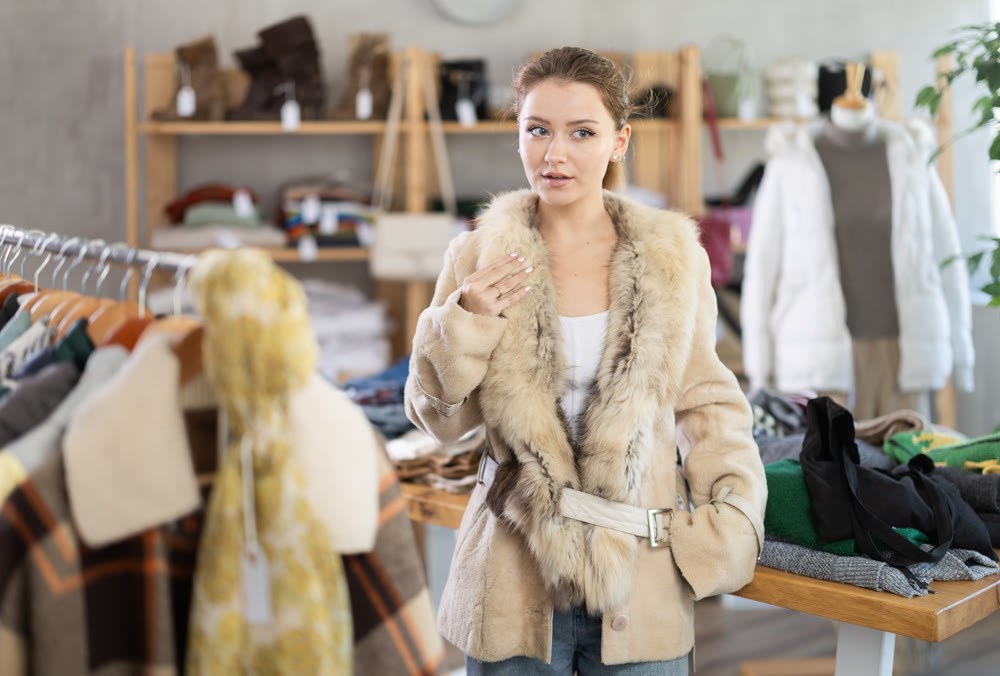 Young woman trying on fur coat in store
