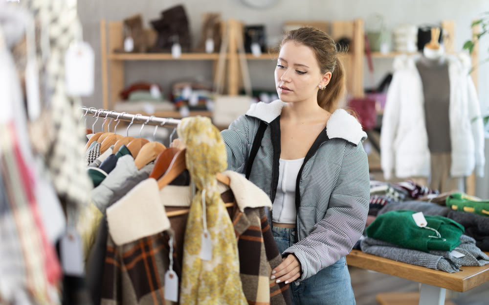 Young girl near showcase examine goods, buying something autumn outwear.