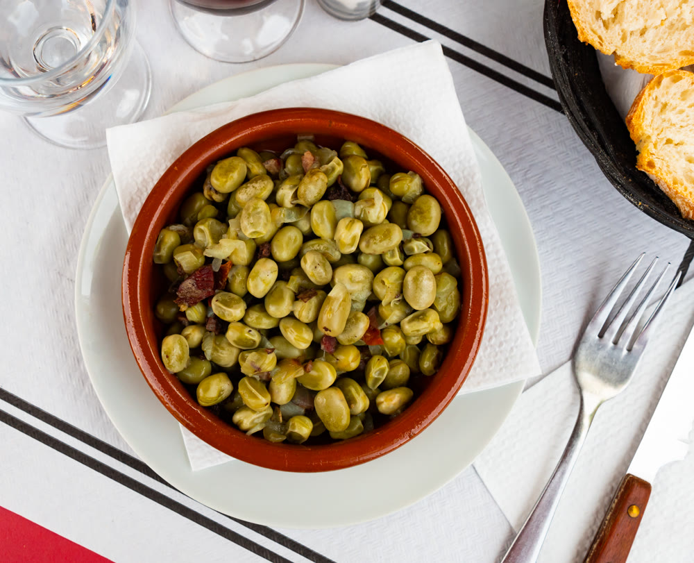 Traditional Catalan faba beans stewed with slices of jamon