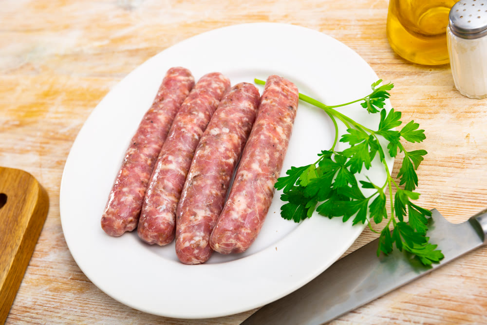 Tasty spiced butifarra, pork sausage with mushrooms with herbs on plate