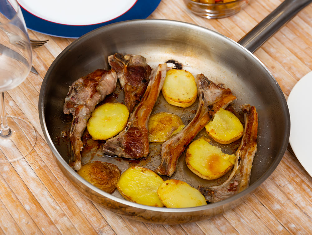 Grilled lamb spare ribs with baked potatoes garnished with greens