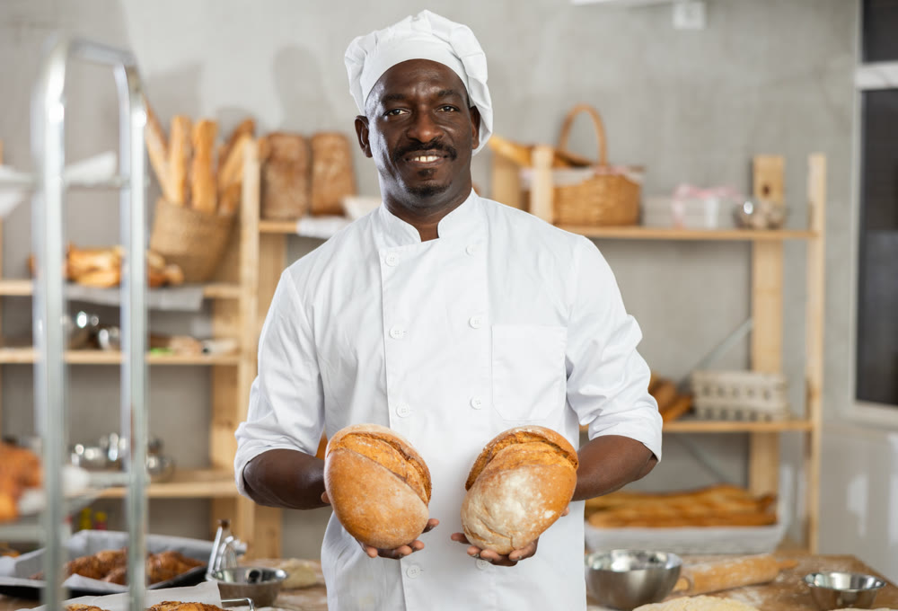 Successful African American baker holding freshly baked bread