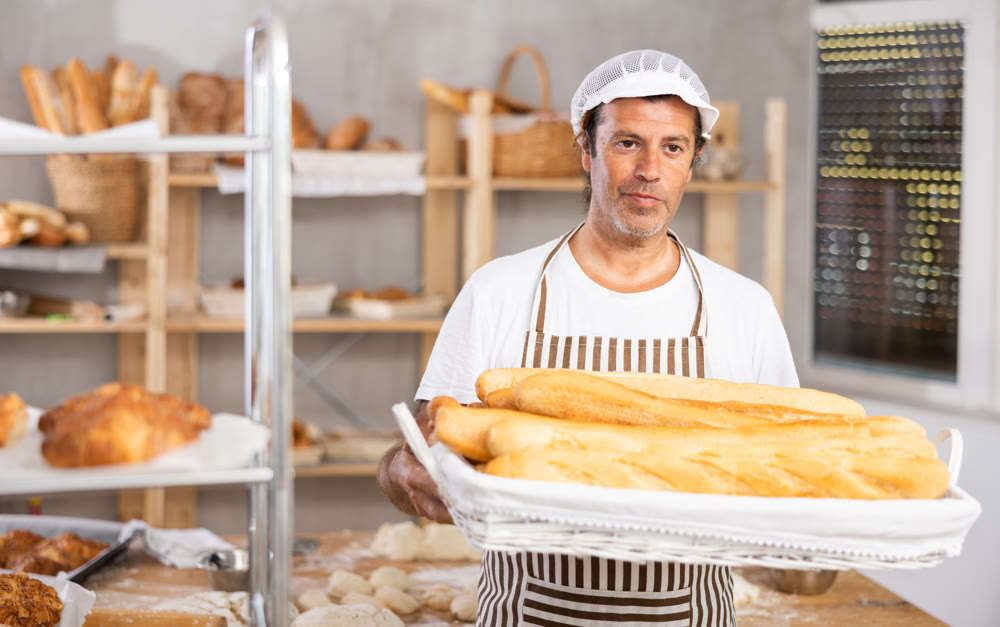 Adult male baker with basket of baguettes
