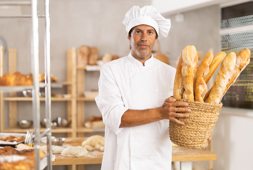 Adult male baker with basket of baguettes