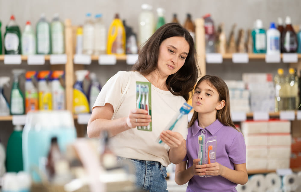Woman with child family selects and studies label toothpaste and toothbrush