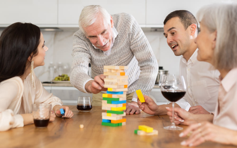 Cheerful senior man playing jenga at family home get-together