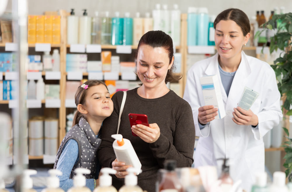 Woman with daughter scanning barcode on skincare lotion to check ingredient