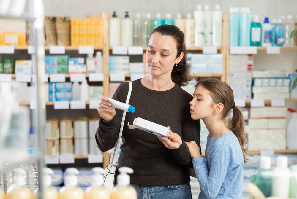Woman with daughter choosing ointment in pharmacy