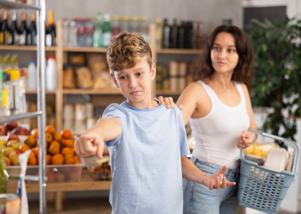 Teen boy quarrels with mother while shopping, he gets angry and turns away from mother