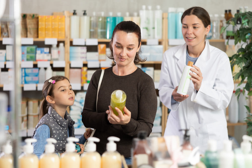 Caring mother choosing dermatologically tested shampoo for daughter