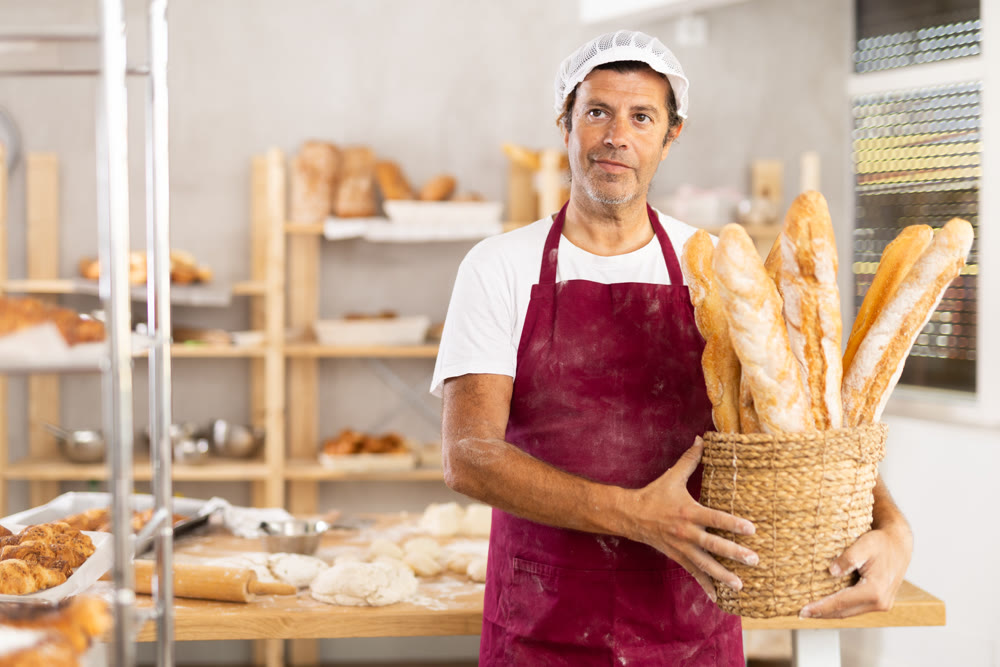 Adult male baker with basket of baguettes