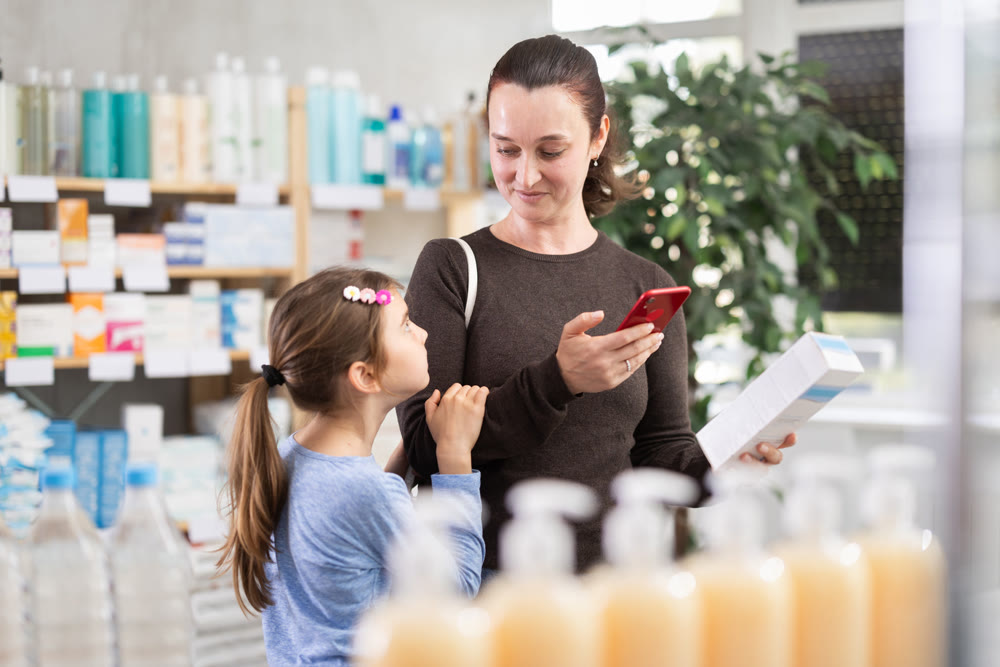woman with a child pays for purchases using a QR code at a pharmacy