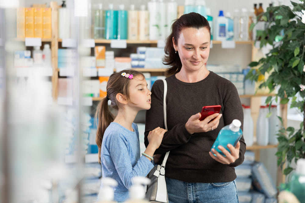 Woman with daughter scanning qr code of mouthwash