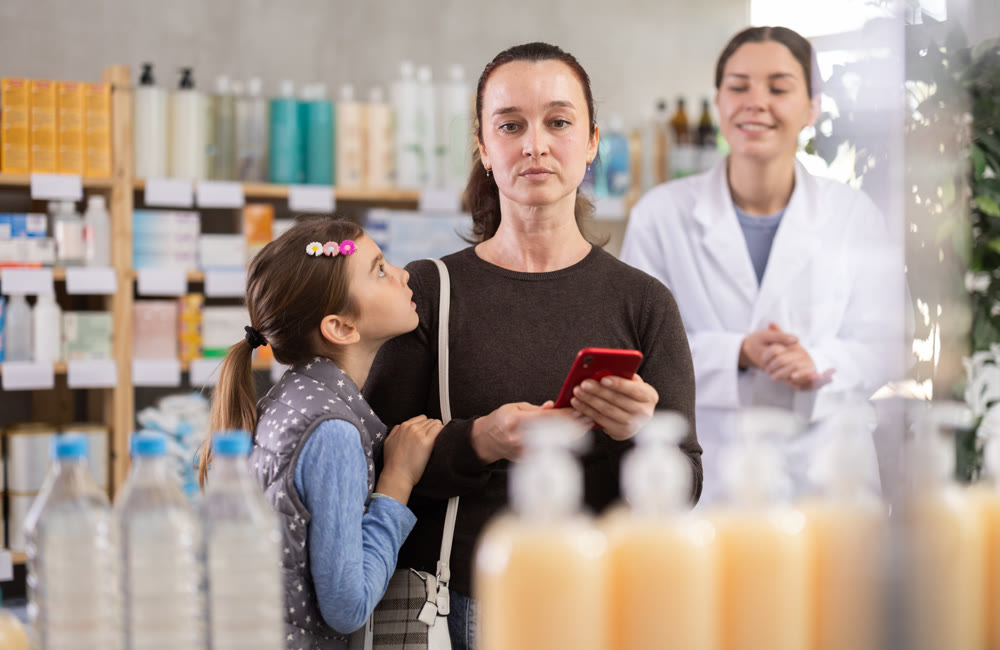 Woman checking prescription details on phone in pharmacy