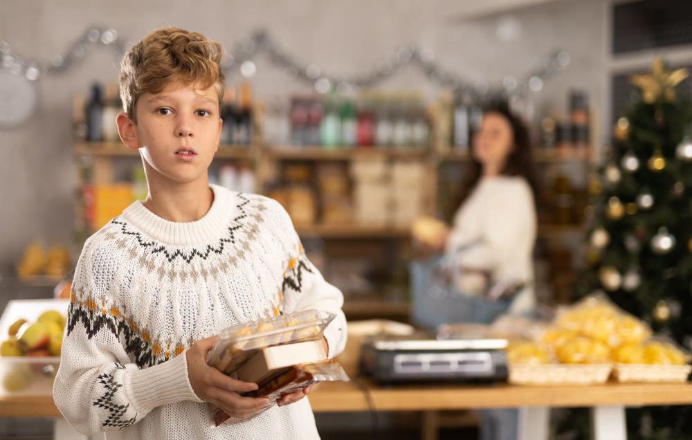 Boy with sweets choosing food at grocery store