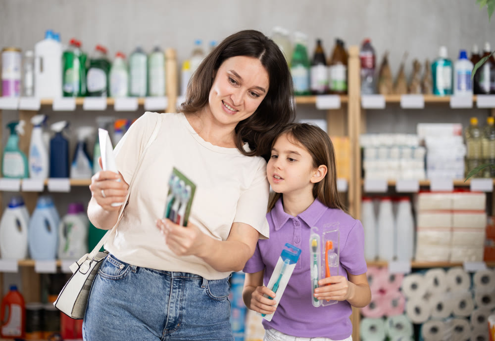 Woman with child family selects and studies label toothpaste and toothbrush