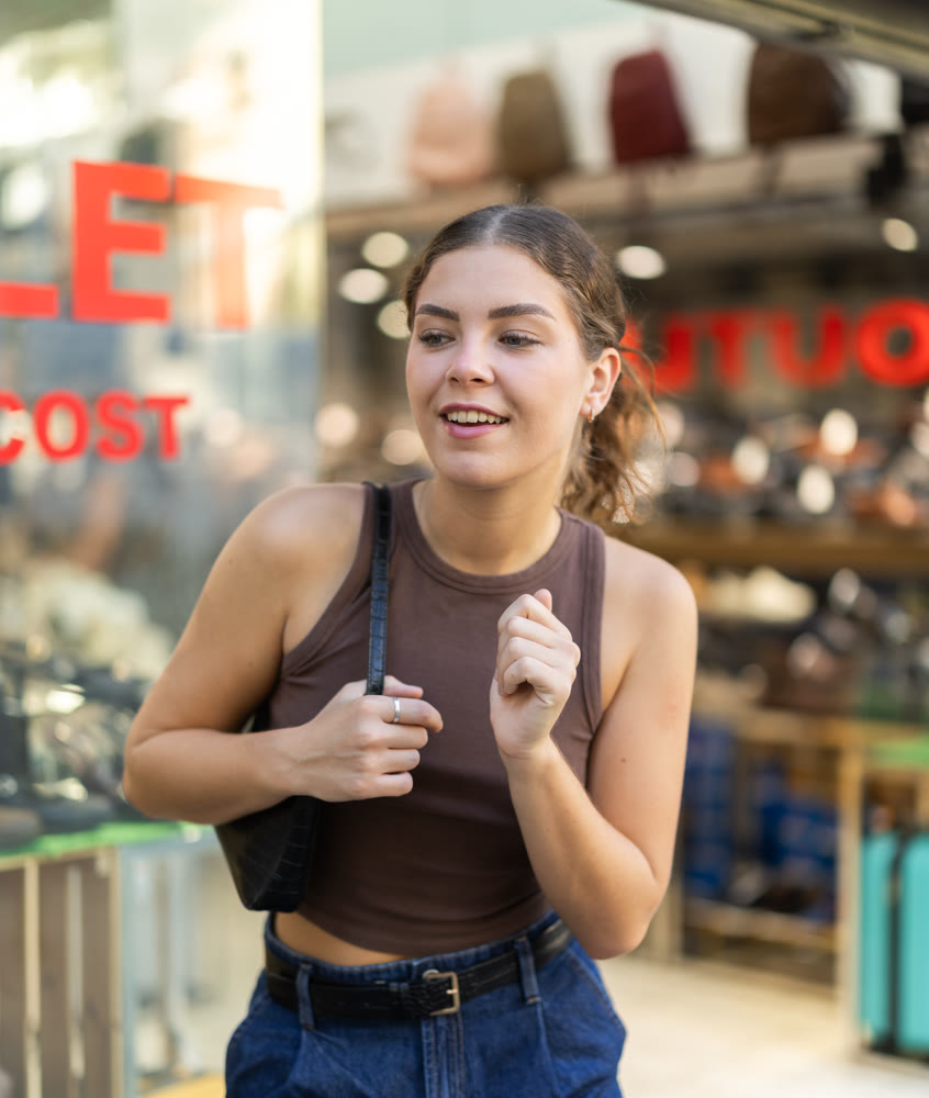 Girl is walking around street market or fair, choosing shoes goods