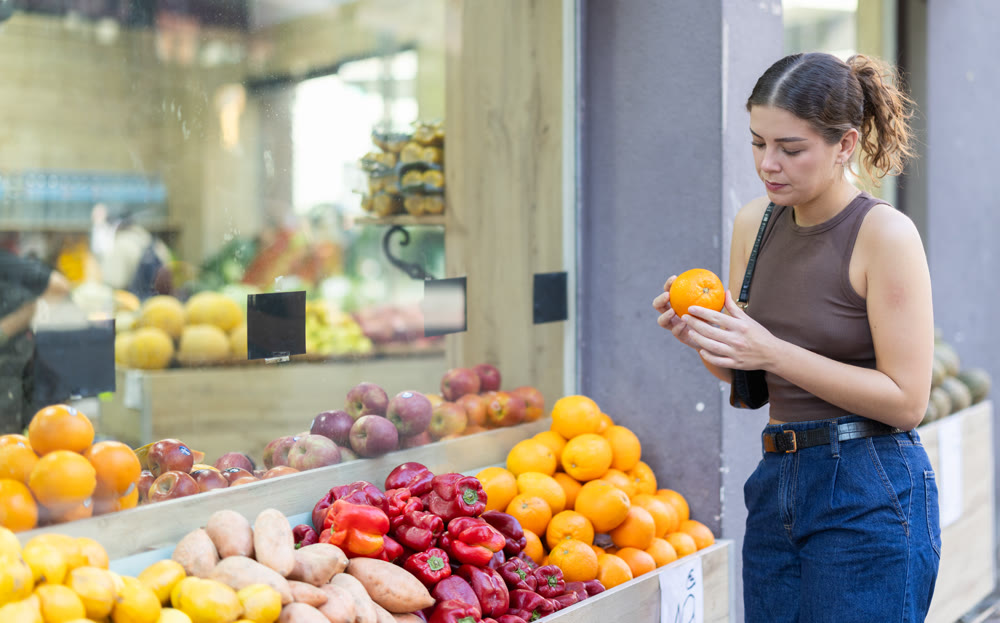 Girl is walking around street market or fair, choosing orange goods