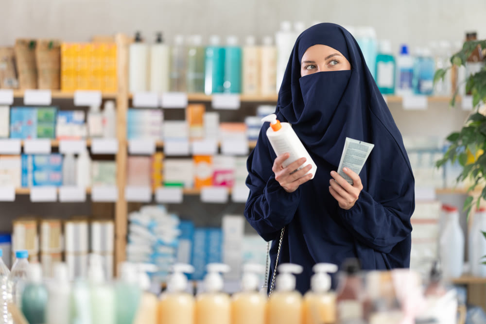 Young woman in hijab chooses cream at pharmacy