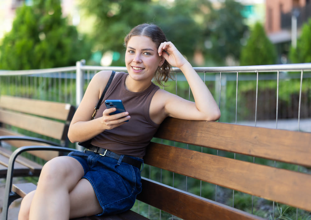 Woman scrolling smartphone while sitting on bench