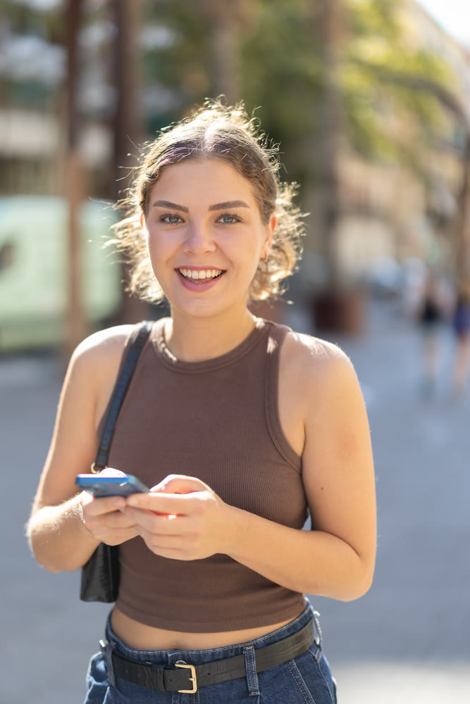 Girl walks around city district with mobile phone