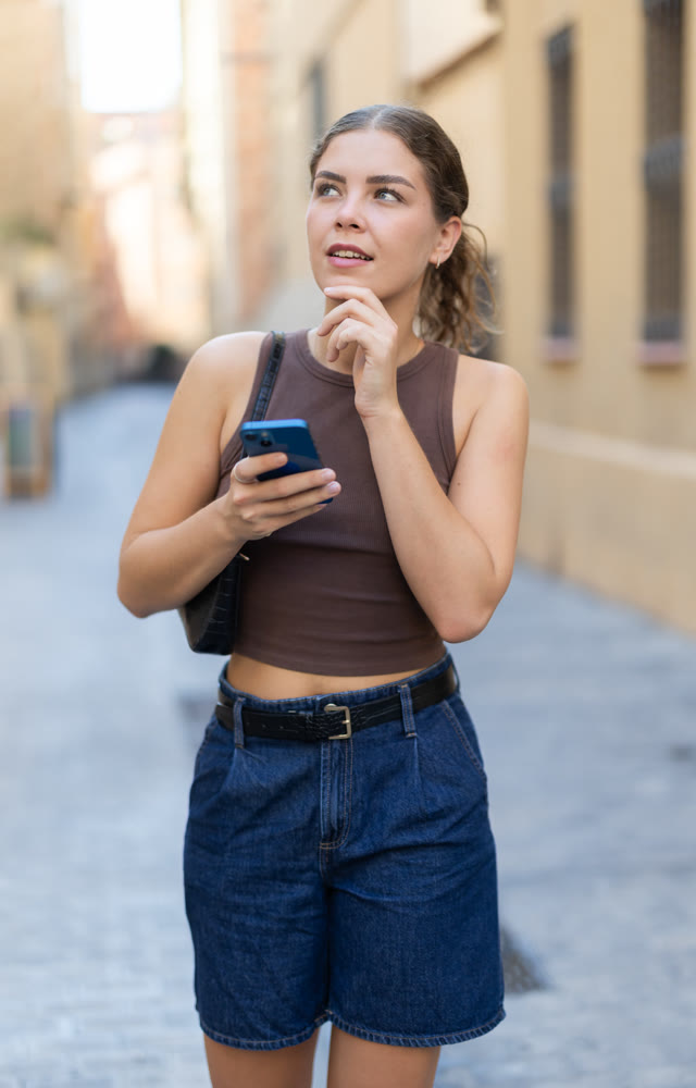 Girl walks around city district with mobile phone