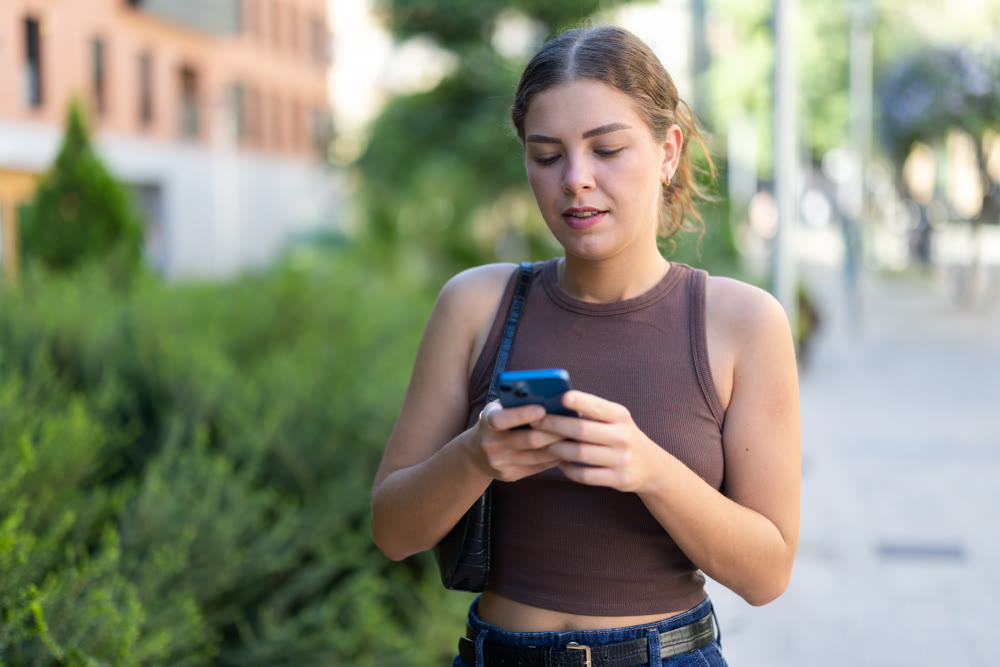 Girl walks around city district with mobile phone