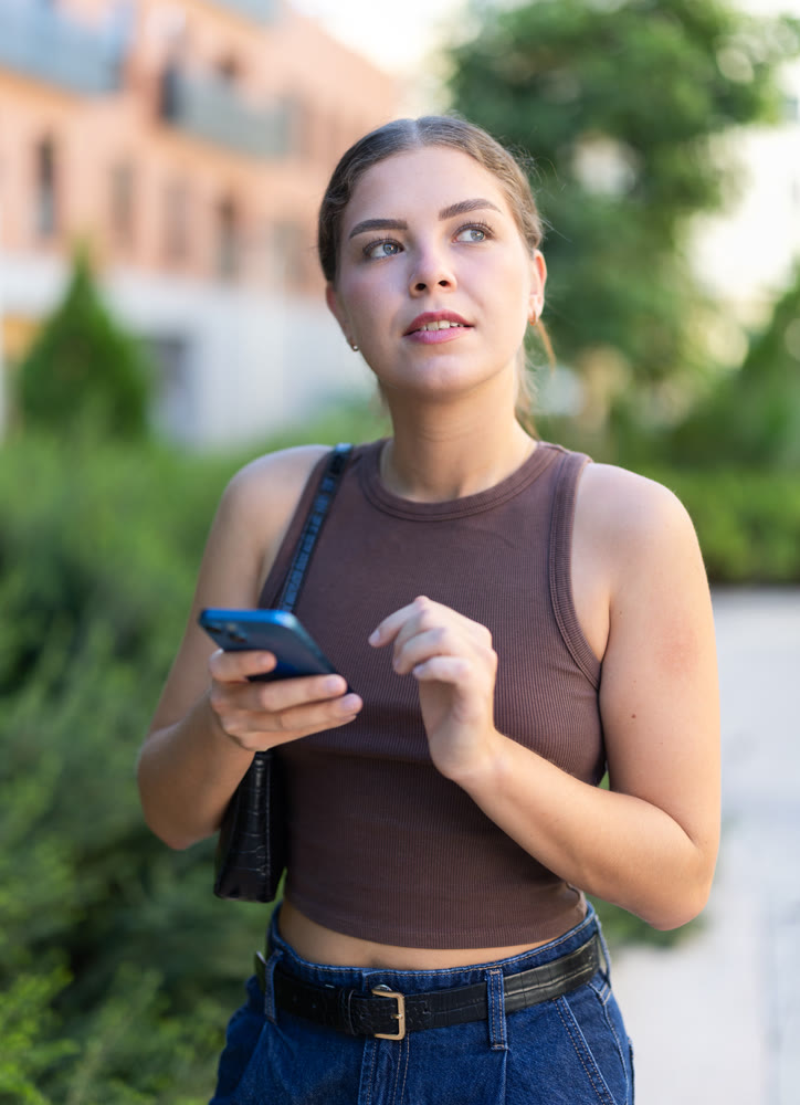 Girl walks around city district with mobile phone