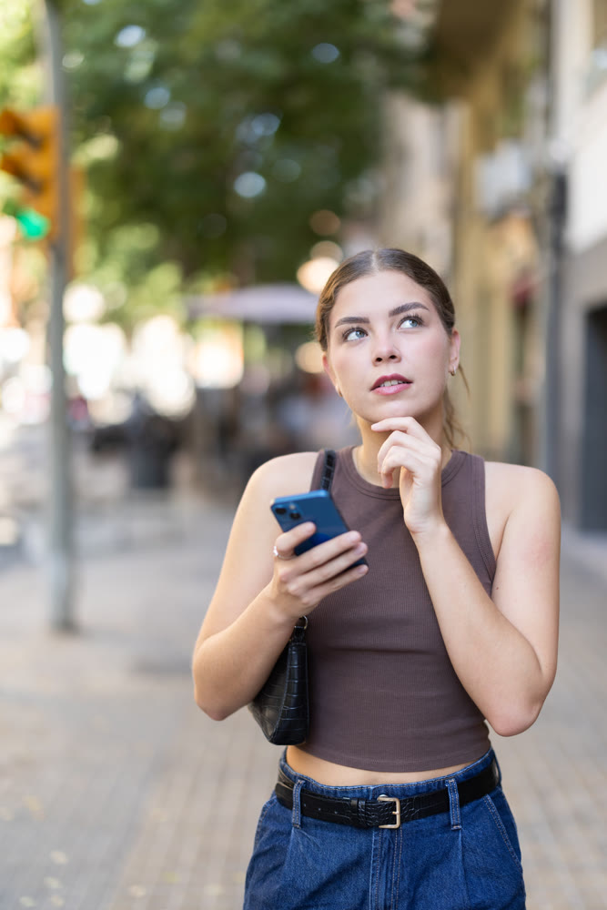 Young woman looking at smartphone while walking along street