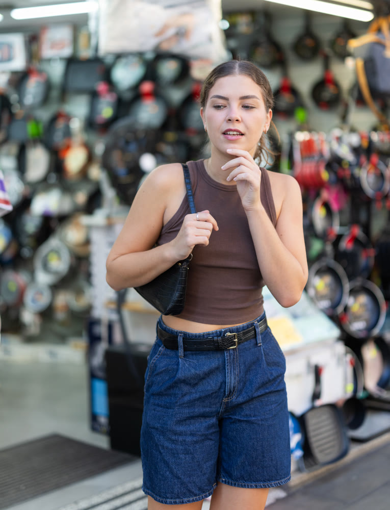 Girl is walking around street market or fair, choosing tableware pans goods