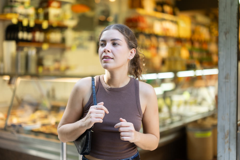 Young woman looking at outdoor grocery store window