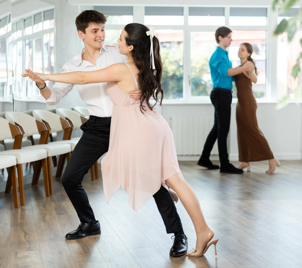 Couple in evening dresses enjoys pair dance tango, interacting with each other on floor