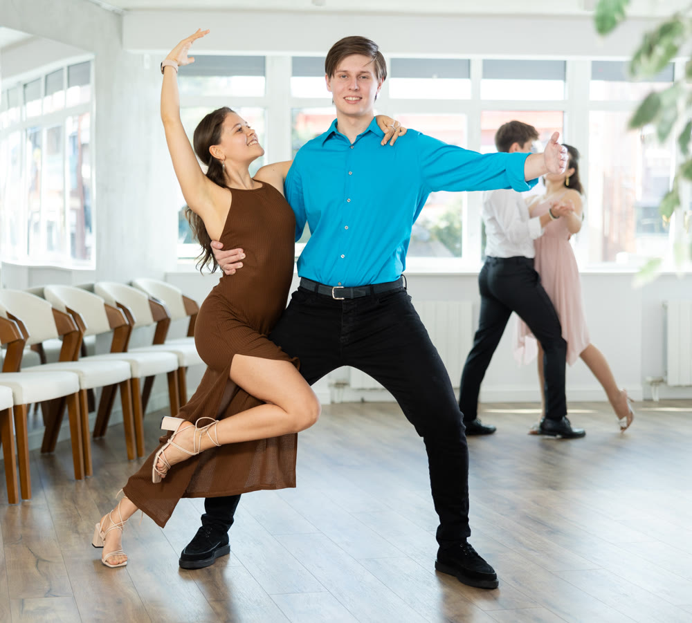 Girl and guy dancing slow ballroom dance during group class in choreography studio