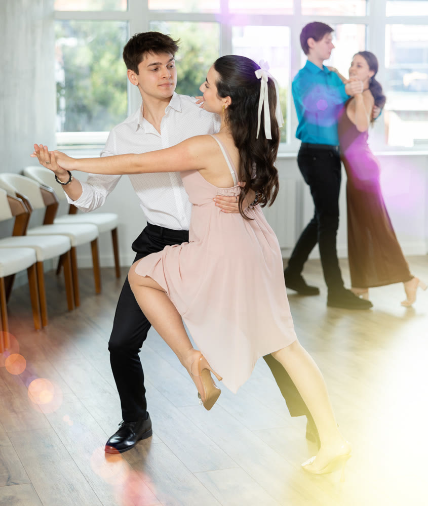 Guy and girl in couple spins to rhythm of tango during lesson for novice students. Classes in mini groups for those who want to learn dancing