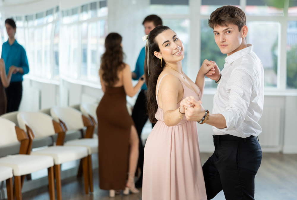 Latin American guy and dark-haired girl performing kizomba in dance studio