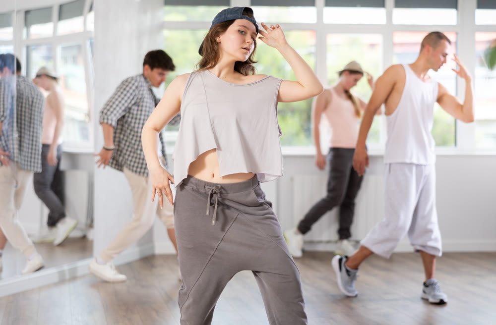 Girl poses against background of hip hop dancing people.