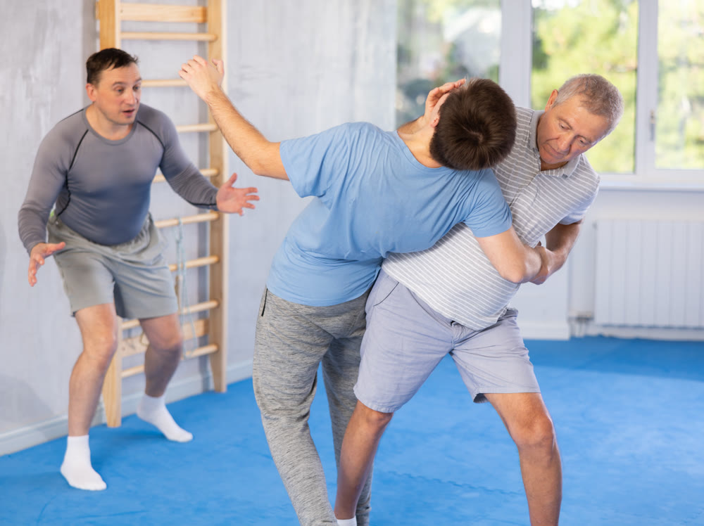 Mature man throws guy to the mat - two men of different ages in judo sparring