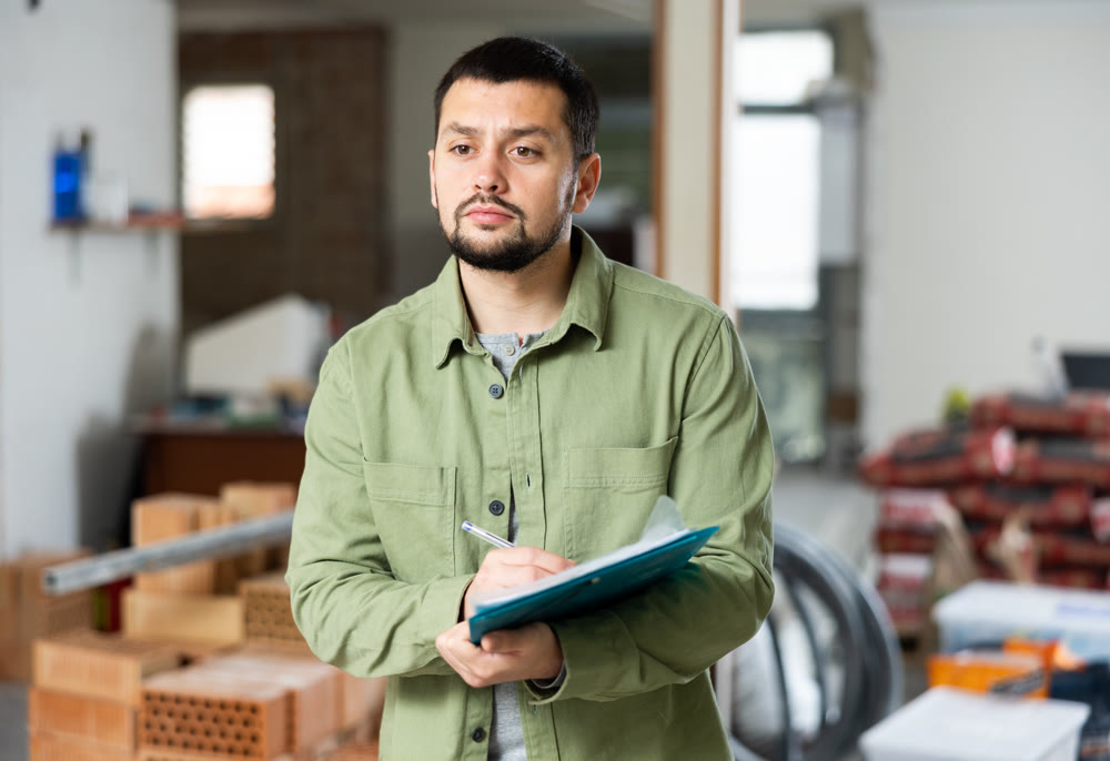 Focused man standing at indoors building site, reading document