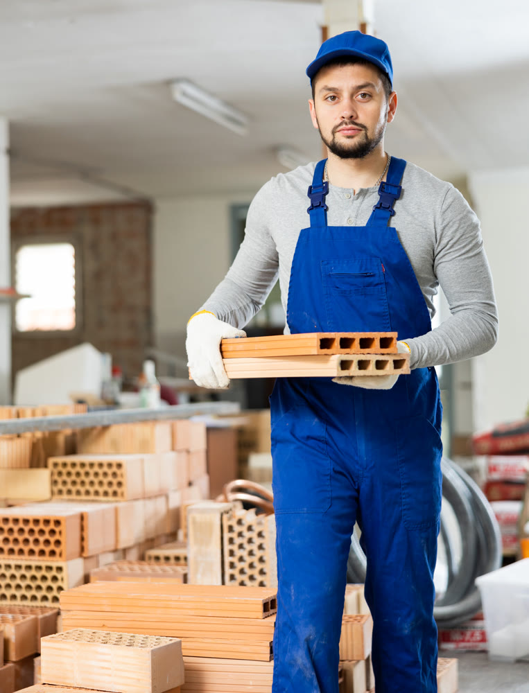 Young man stacking bricks at construction site
