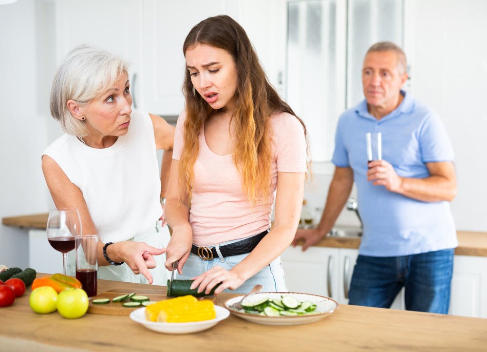 Mother-in-law teaches young daughter-in-law to cook dinner in kitchen