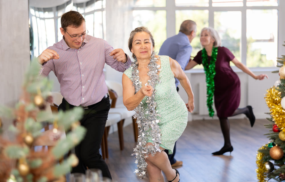 Group of adult active people dancing twist or rock and roll dance in dance hall during celebration Christmas and New Year
