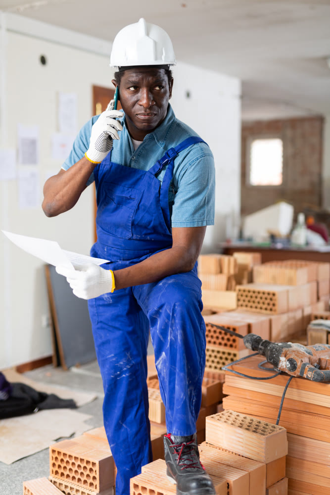 Man construction worker having telephone conversation about documentation