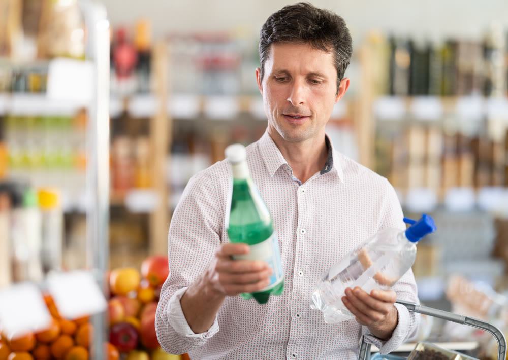Man in light shirt choose and buy soda water in store