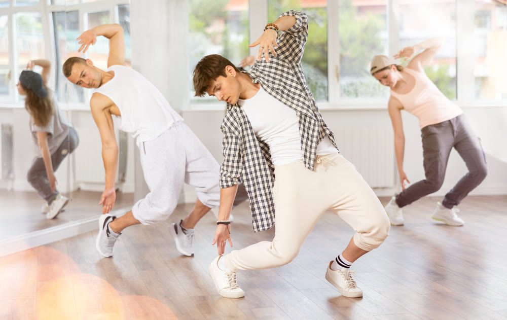 Group of young people perform choreographic exercises and teaches energetic mobile social dance waacking together