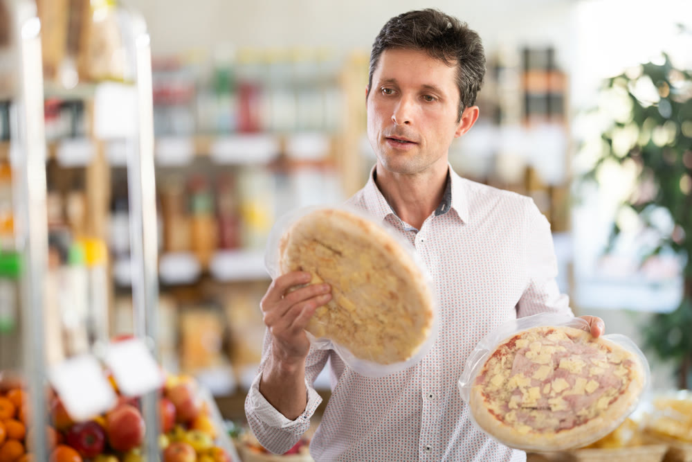 Adult man choosing pizza in grocery store