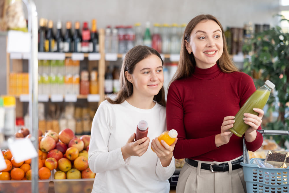 Teenage girl and her mother choosing smoothie in grocery store