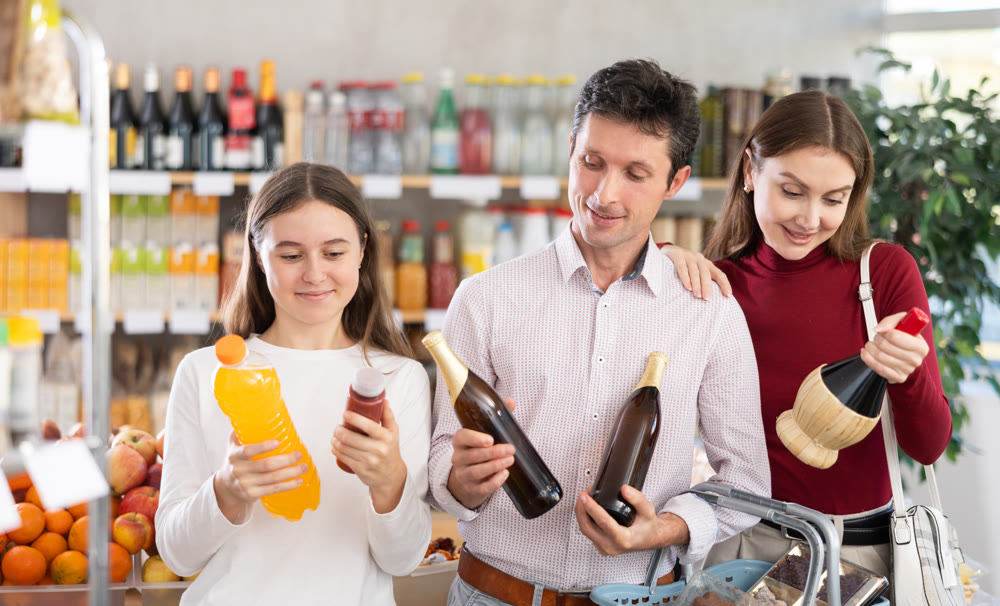 Father, mother and daughter choose wine, beer and soda water drinks in shop