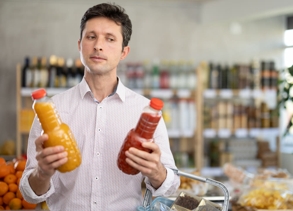 Man in light shirt choose and buy juice in store