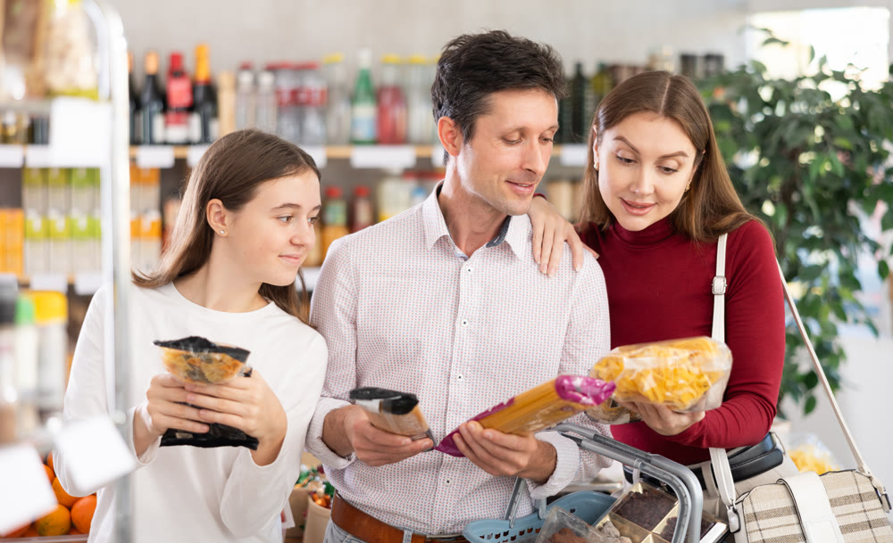 Dad, mom and daughter look at and choose pasta in selling area of shop